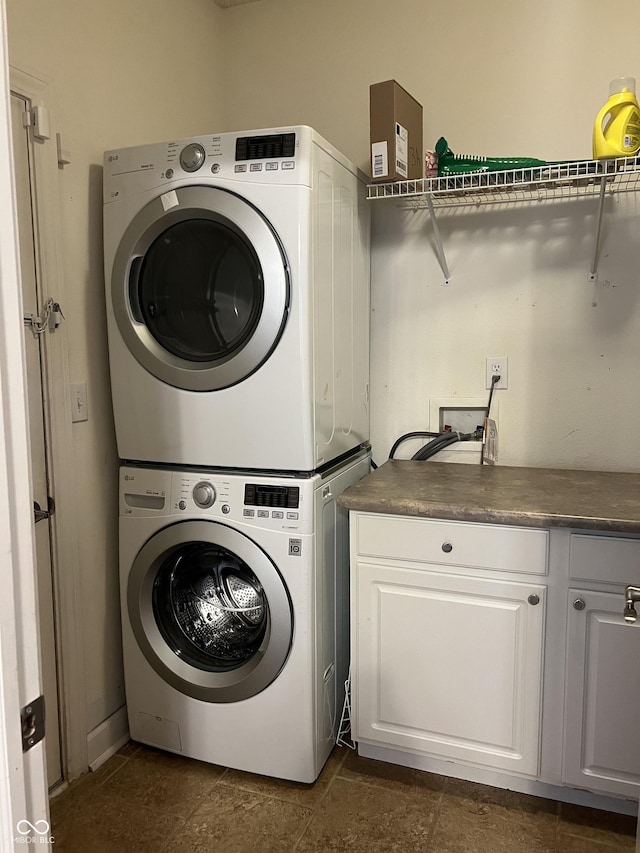 clothes washing area featuring cabinet space and stacked washing maching and dryer