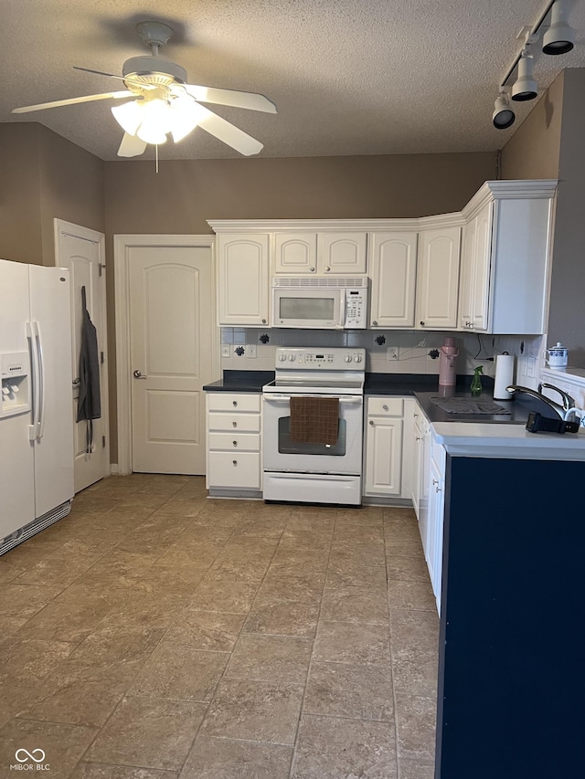 kitchen with white appliances, dark countertops, ceiling fan, and white cabinetry