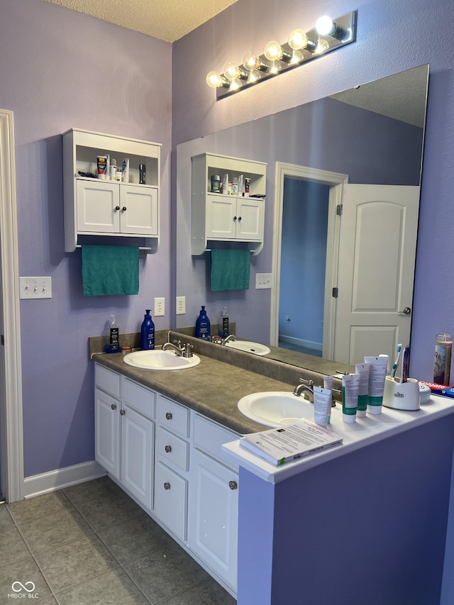 full bath featuring a sink, a textured ceiling, double vanity, and tile patterned flooring