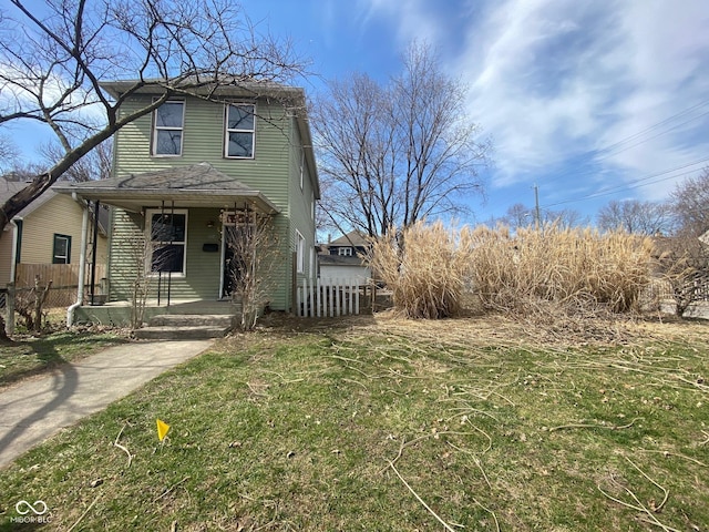 view of front facade with covered porch, a front yard, and fence