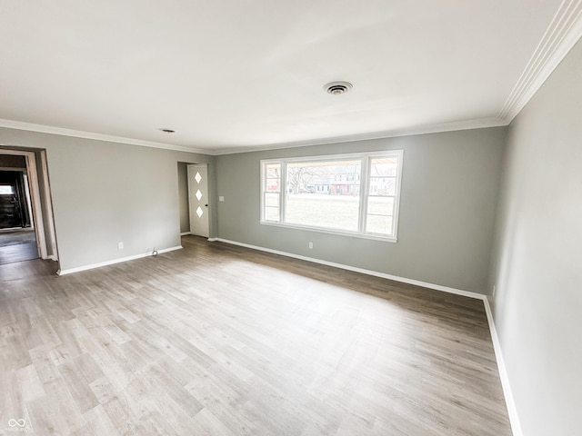 unfurnished room featuring visible vents, ornamental molding, baseboards, and wood finished floors