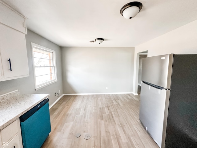 kitchen featuring light wood-type flooring, freestanding refrigerator, white cabinets, dishwashing machine, and baseboards