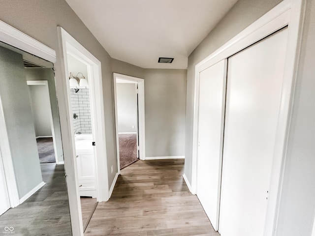 hall with light wood-style flooring and baseboards