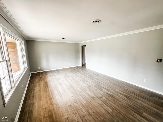 spare room with visible vents, crown molding, baseboards, and wood finished floors