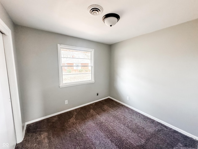 unfurnished room featuring baseboards, visible vents, and dark carpet