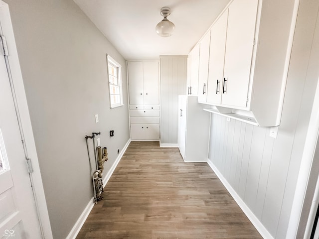 clothes washing area featuring cabinet space, light wood-type flooring, and baseboards