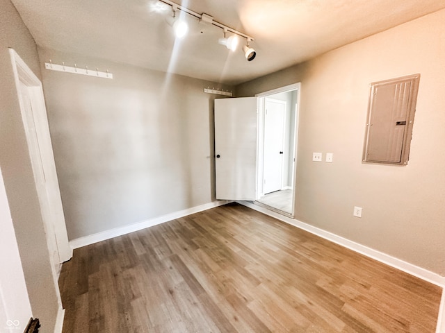 empty room featuring electric panel, baseboards, and wood finished floors