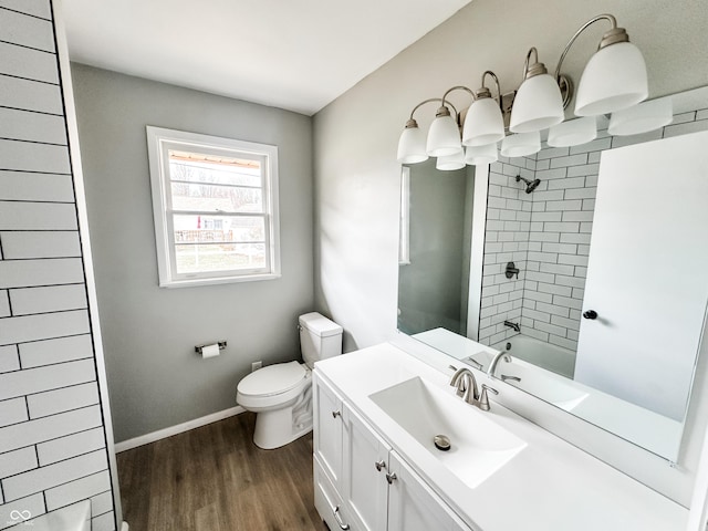 bathroom with baseboards, toilet, shower / bathtub combination, wood finished floors, and vanity