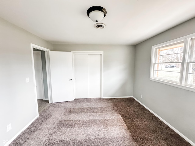 unfurnished bedroom with carpet flooring, baseboards, visible vents, and a closet