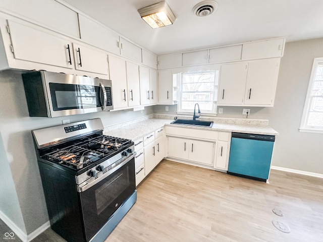 kitchen featuring light countertops, a wealth of natural light, appliances with stainless steel finishes, and a sink