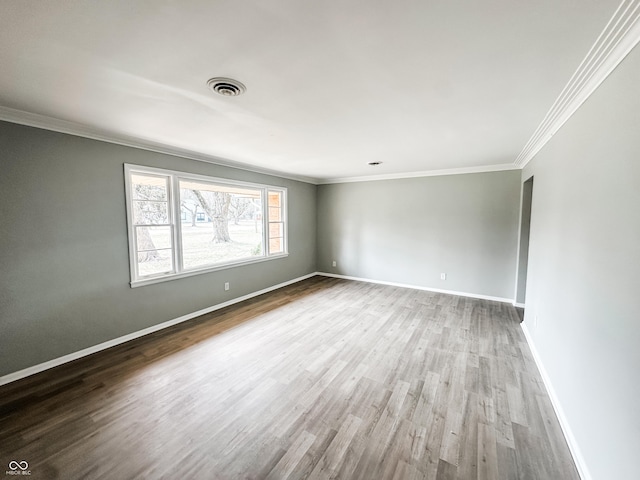 spare room featuring visible vents, ornamental molding, baseboards, and wood finished floors