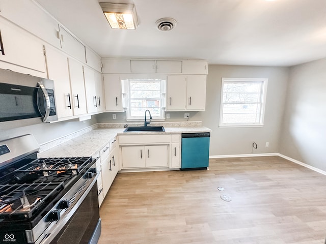 kitchen featuring visible vents, light countertops, light wood-style flooring, appliances with stainless steel finishes, and a sink