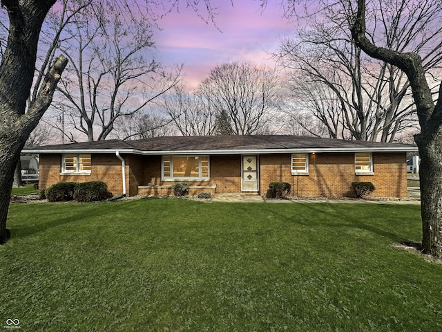 single story home with brick siding and a yard