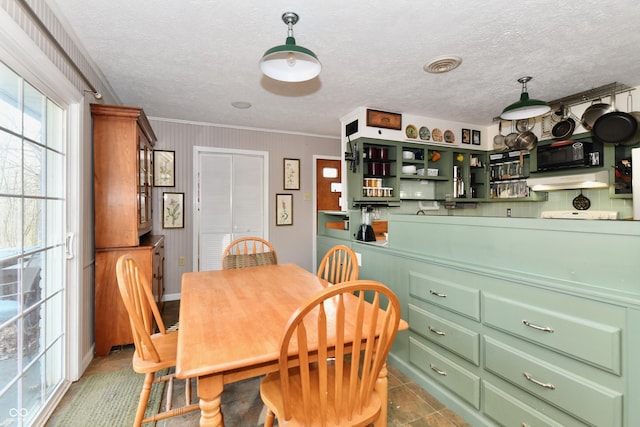 dining space featuring visible vents, a textured ceiling, and ornamental molding