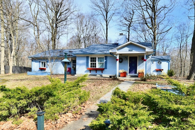 ranch-style home with brick siding, a chimney, and fence