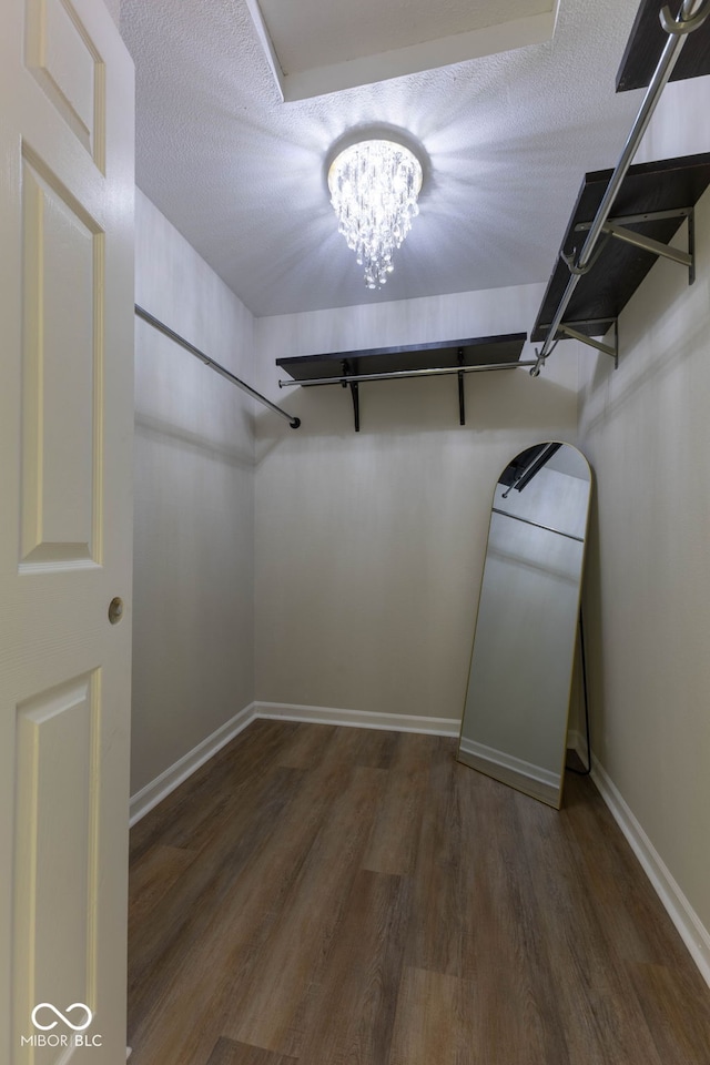 spacious closet with a notable chandelier and wood finished floors