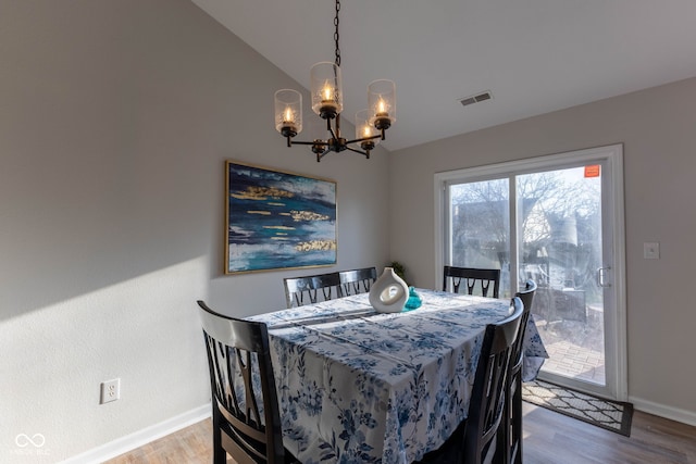 dining space with vaulted ceiling, a notable chandelier, wood finished floors, and baseboards