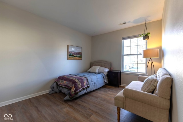 bedroom with visible vents, baseboards, and wood finished floors