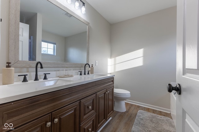 full bath with double vanity, wood finished floors, toilet, and a sink