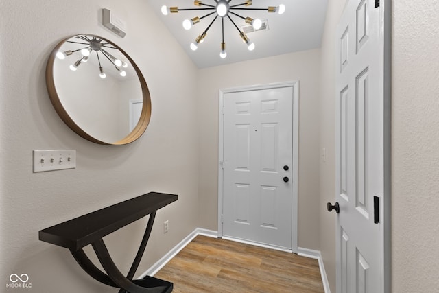 entryway featuring baseboards, an inviting chandelier, and light wood finished floors