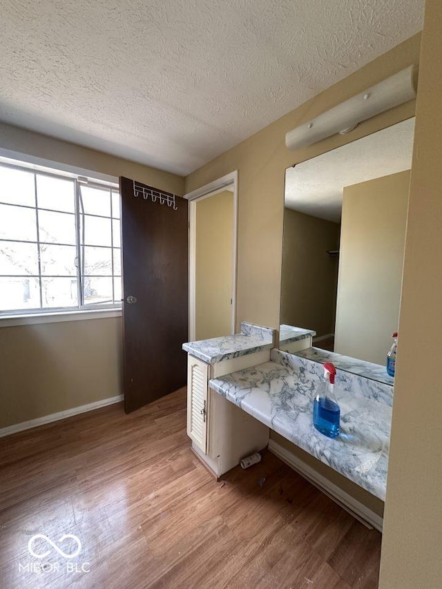 bathroom with a textured ceiling, vanity, baseboards, and wood finished floors