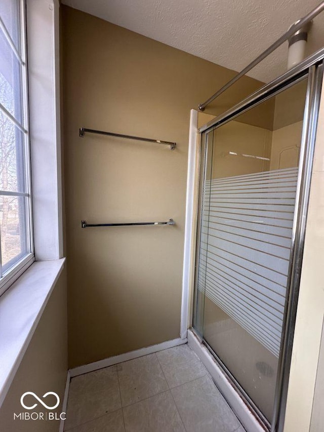 full bathroom with baseboards, a textured ceiling, a stall shower, and tile patterned flooring