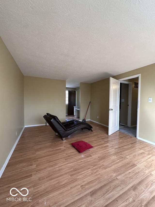 workout room with light wood-type flooring, baseboards, and a textured ceiling