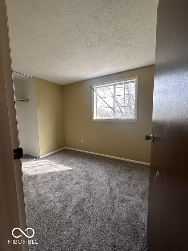 carpeted empty room with baseboards and a textured ceiling