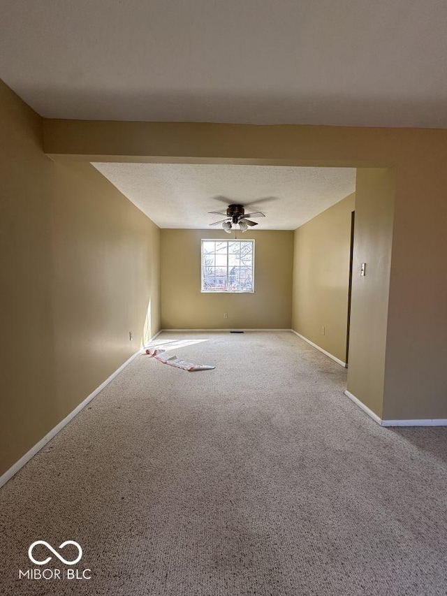 carpeted spare room with baseboards, a textured ceiling, and ceiling fan