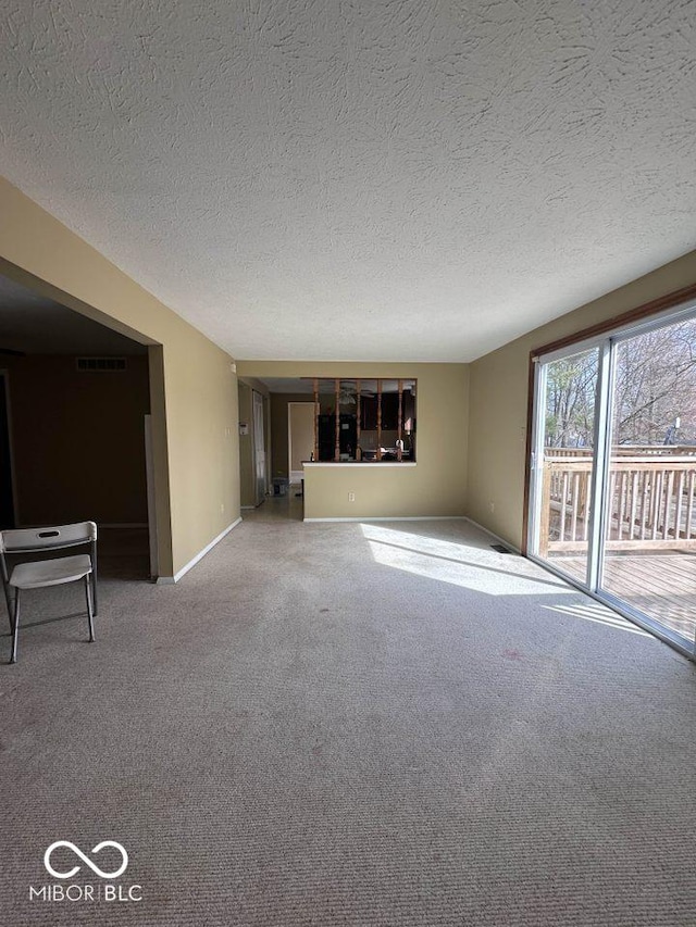 unfurnished living room featuring carpet flooring, baseboards, visible vents, and a textured ceiling