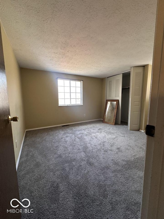 unfurnished bedroom featuring baseboards, a textured ceiling, and carpet floors