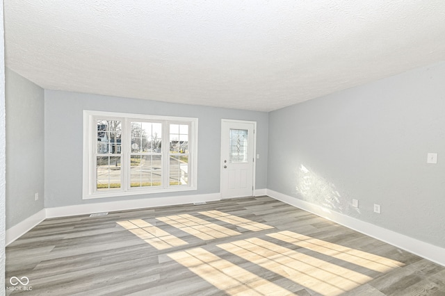 foyer featuring a textured ceiling, baseboards, and wood finished floors