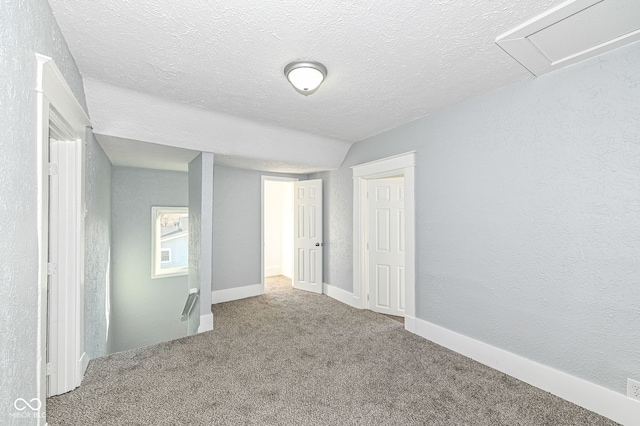 unfurnished bedroom featuring baseboards, a textured ceiling, a textured wall, and carpet floors