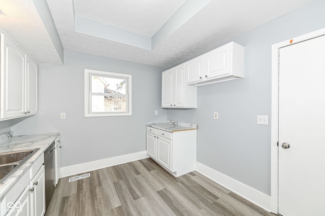 laundry room featuring visible vents, baseboards, a sink, light wood-style floors, and a textured ceiling