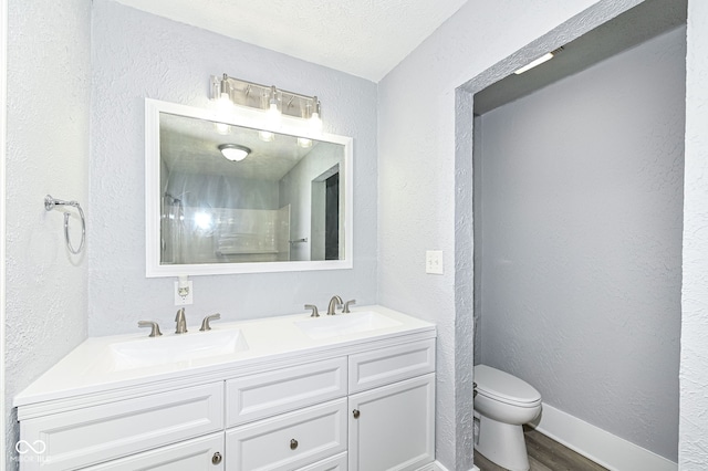 bathroom with toilet, a textured wall, and a sink