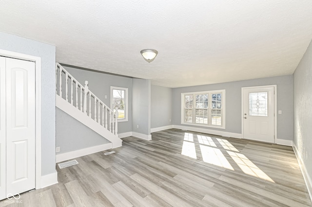 foyer entrance featuring stairway, baseboards, and wood finished floors