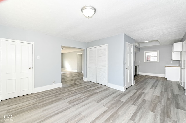 unfurnished living room featuring baseboards, a textured ceiling, and light wood-style flooring