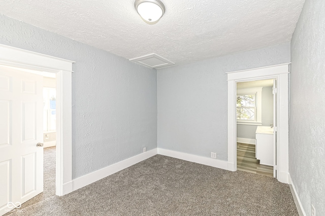 unfurnished bedroom with attic access, a textured wall, and a textured ceiling