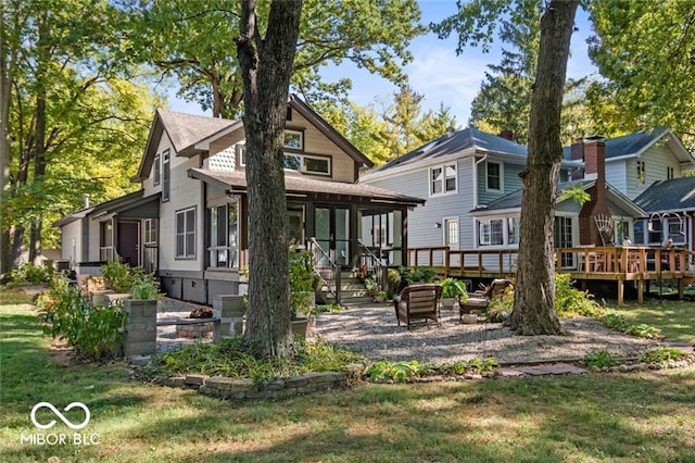 back of property featuring a deck and a lawn