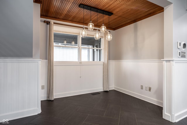 unfurnished dining area featuring wooden ceiling, visible vents, and a wainscoted wall