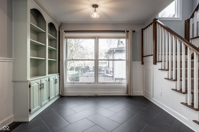 unfurnished dining area with stairway and dark tile patterned flooring