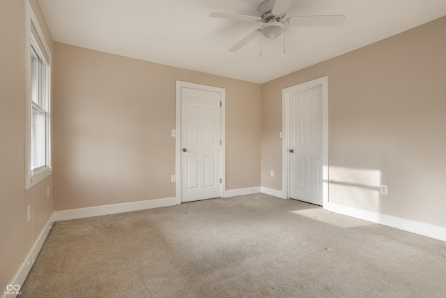 carpeted spare room featuring baseboards and ceiling fan