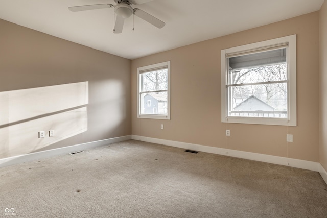 carpeted empty room featuring visible vents, baseboards, and ceiling fan