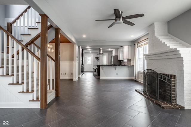 living area with a ceiling fan, recessed lighting, a fireplace, baseboards, and stairs