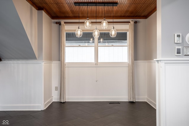 unfurnished dining area with visible vents, wainscoting, wooden ceiling, and crown molding