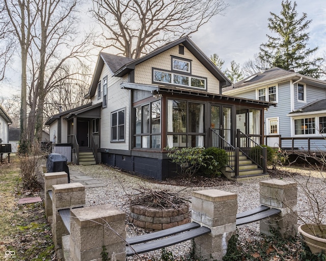 back of house featuring a fire pit, roof with shingles, and a sunroom