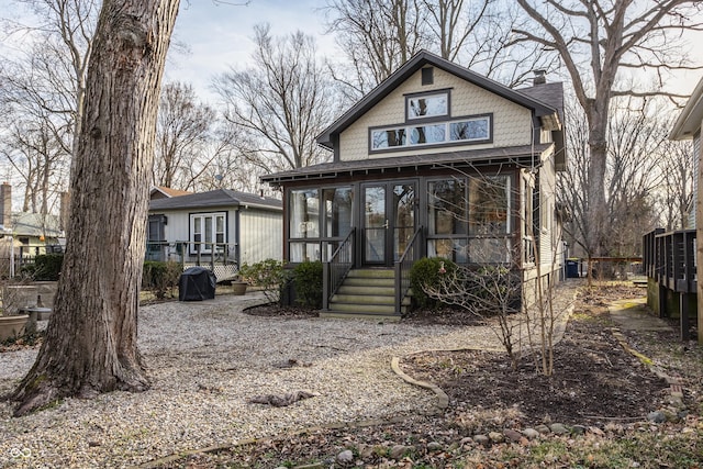 view of front of home featuring french doors, a wooden deck, a chimney, and a sunroom