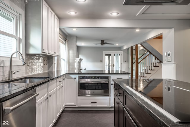 kitchen with a sink, dark stone countertops, backsplash, appliances with stainless steel finishes, and white cabinets