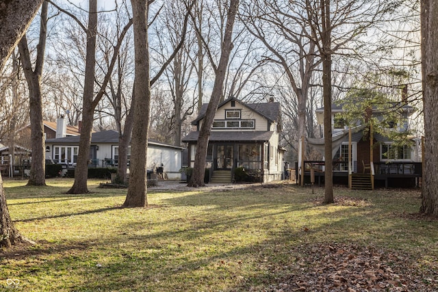 rear view of house featuring a deck, a chimney, and a yard