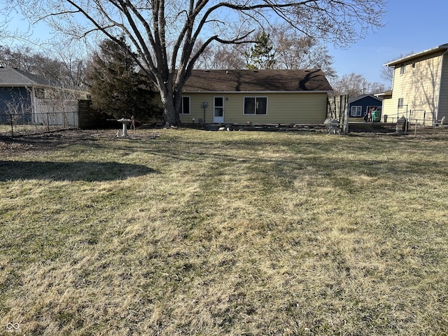 rear view of property featuring a lawn and fence